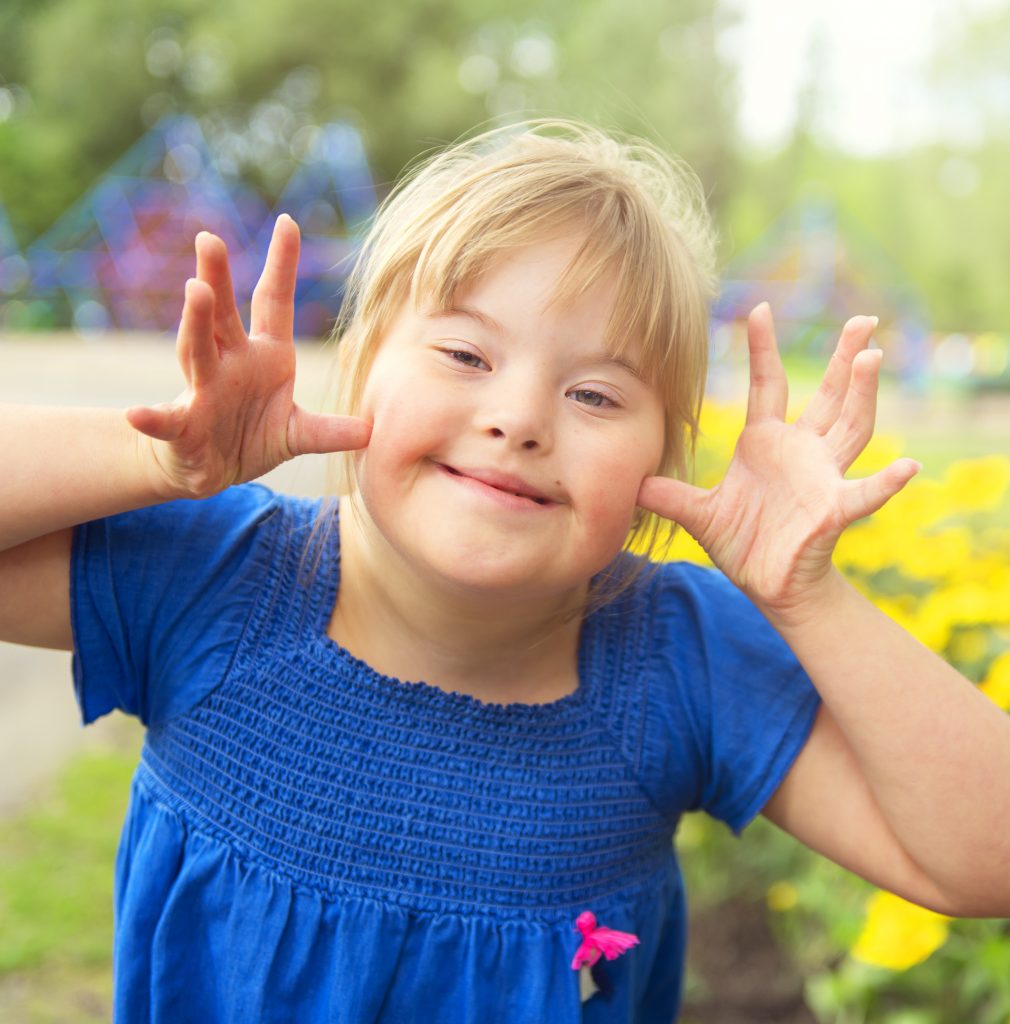 A Portrait Of Trisomie 21 Child Girl Outside Having Fun On A Par